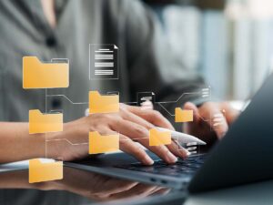 Businessfrau arbeitet an einem Laptop mit einem digitalen Dokumentenmanagement-System; umgeben von Symbolen für Ordner, Dateien und Cloud-Speicher – symbolisiert effiziente, papierlose Büroorganisation.