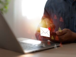 Nutzer mit Smartphone vor Laptop, umgeben von Warnsymbolen – Outlook reagiert nicht und verursacht E-Mail-Probleme