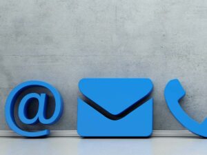 Blaue Symbole für E-Mail, Briefumschlag und Telefon vor grauer Wand – Kontaktmöglichkeiten visualisiert