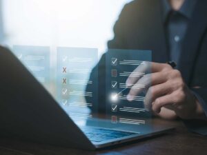 Person arbeitet am Laptop und markiert digitale Checkliste mit Häkchen und Kreuzsymbolen, Konzept für Online-Formulare und Aufgabenverwaltung